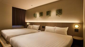 A hotel room with two beds, a wall-mounted light, and a wooden headboard.