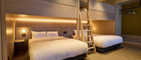 Habitación de hotel con dos camas, una escalera, una mesita de noche y una lámpara fijada a la pared.