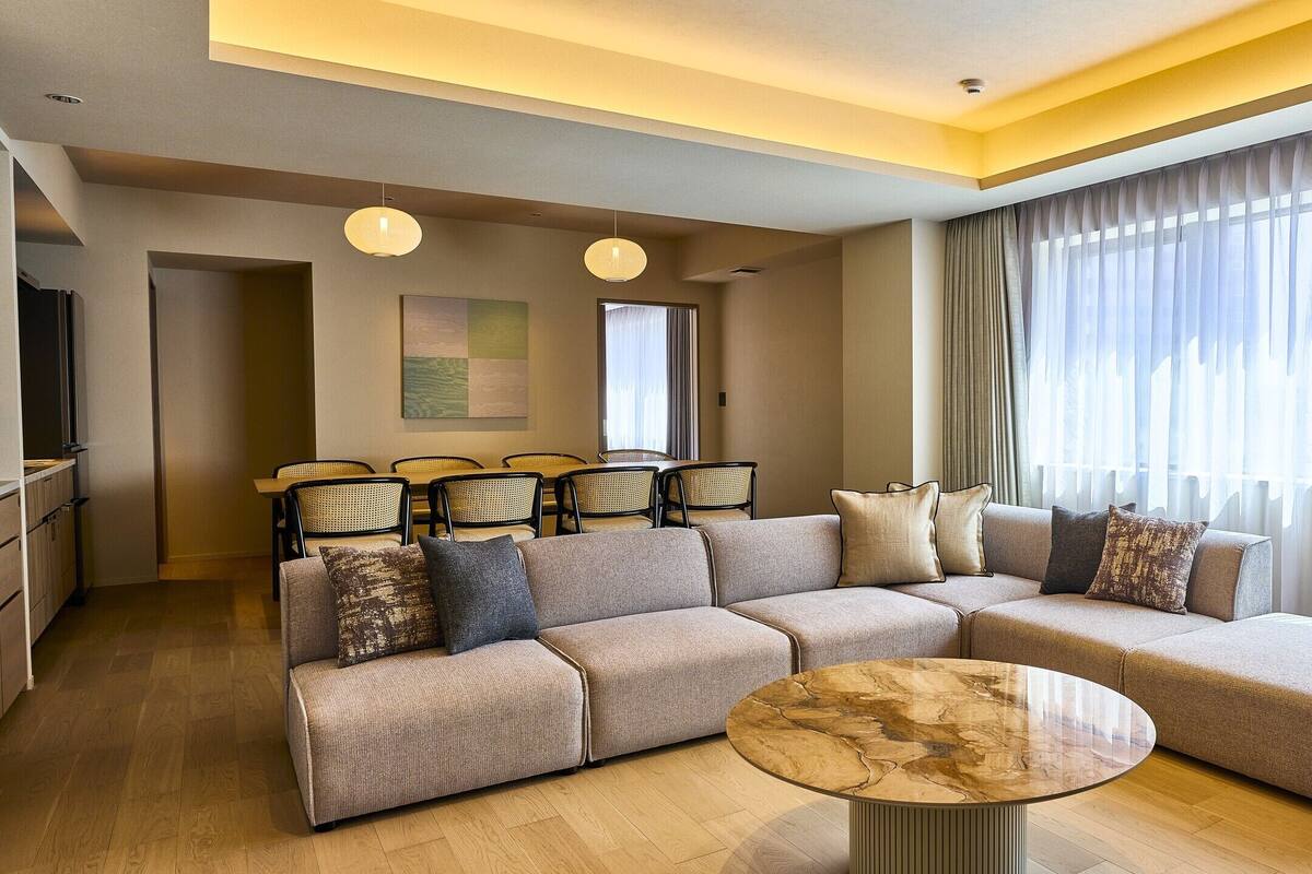 Una sala de estar moderna con un sofá modular, una mesa de centro redonda y un comedor con sillas y una mesa.
