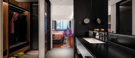 Un baño de hotel moderno con un espejo grande, un lavamanos y un vestidor.