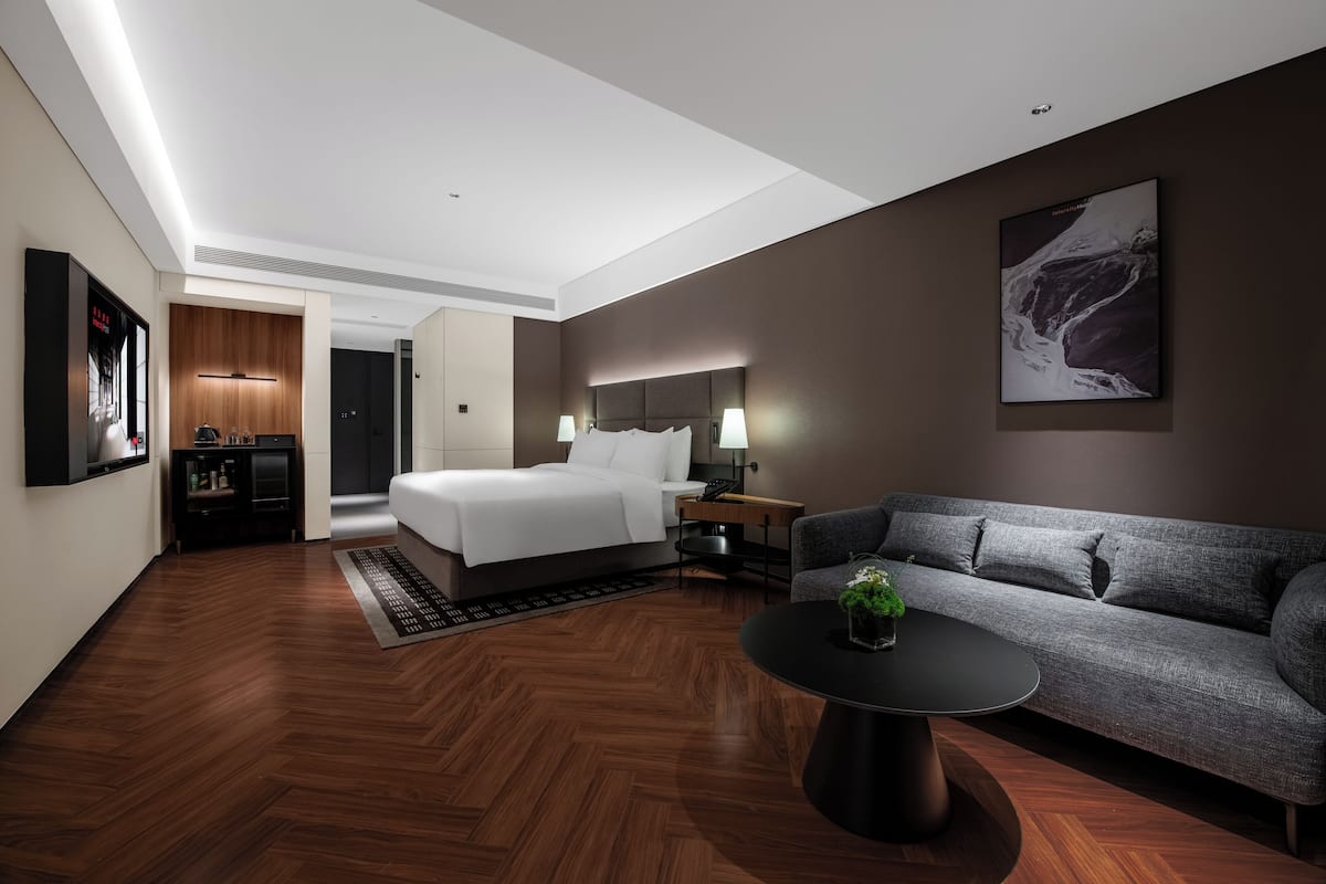 Una habitación de hotel moderna con cama, sofá y mesa de centro.