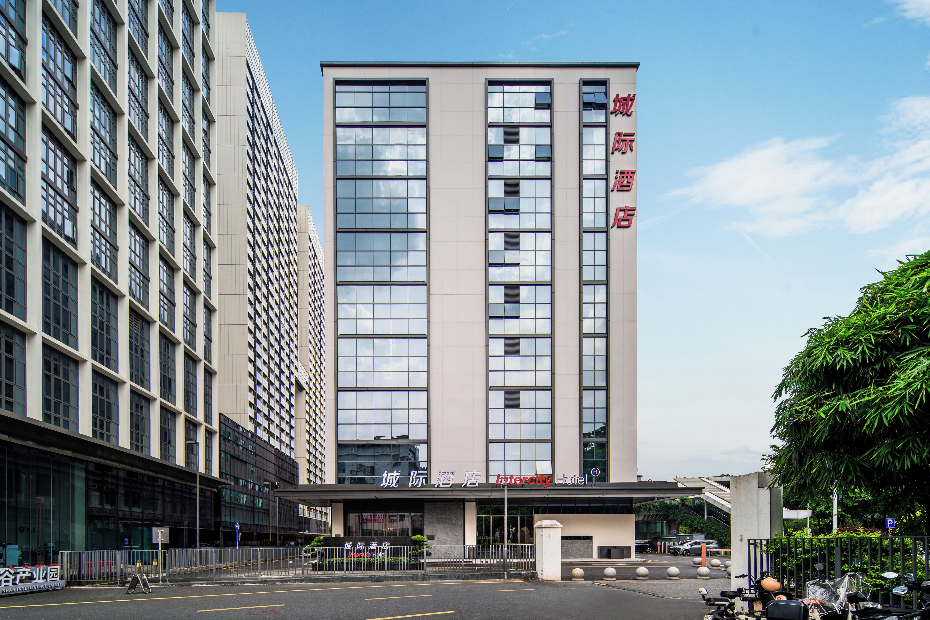 A modern hotel building with a prominent entrance, large windows, and a sign indicating it is a hotel.