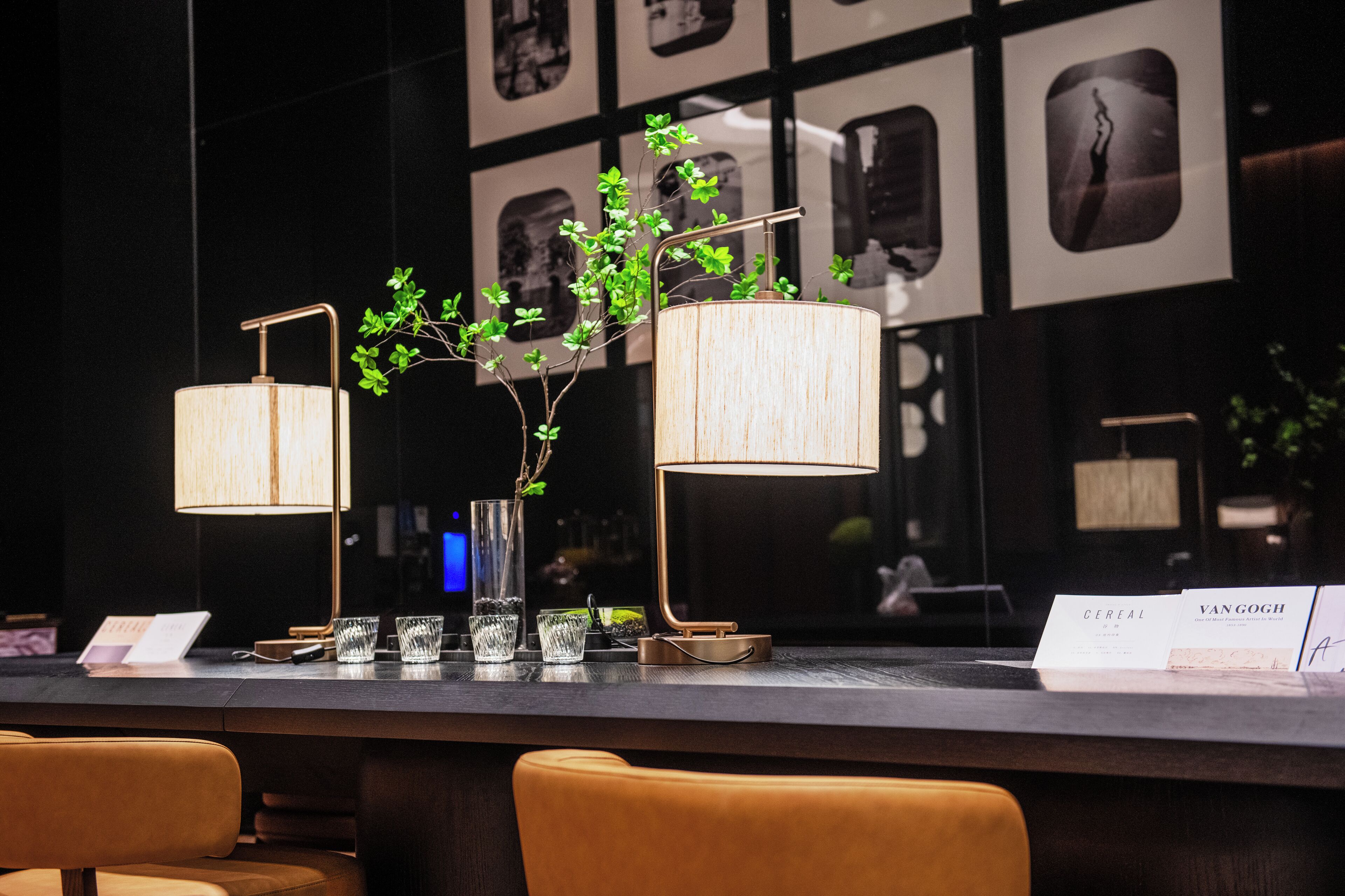 A bar area with two lamps, a vase with green branches, and a menu on the counter.