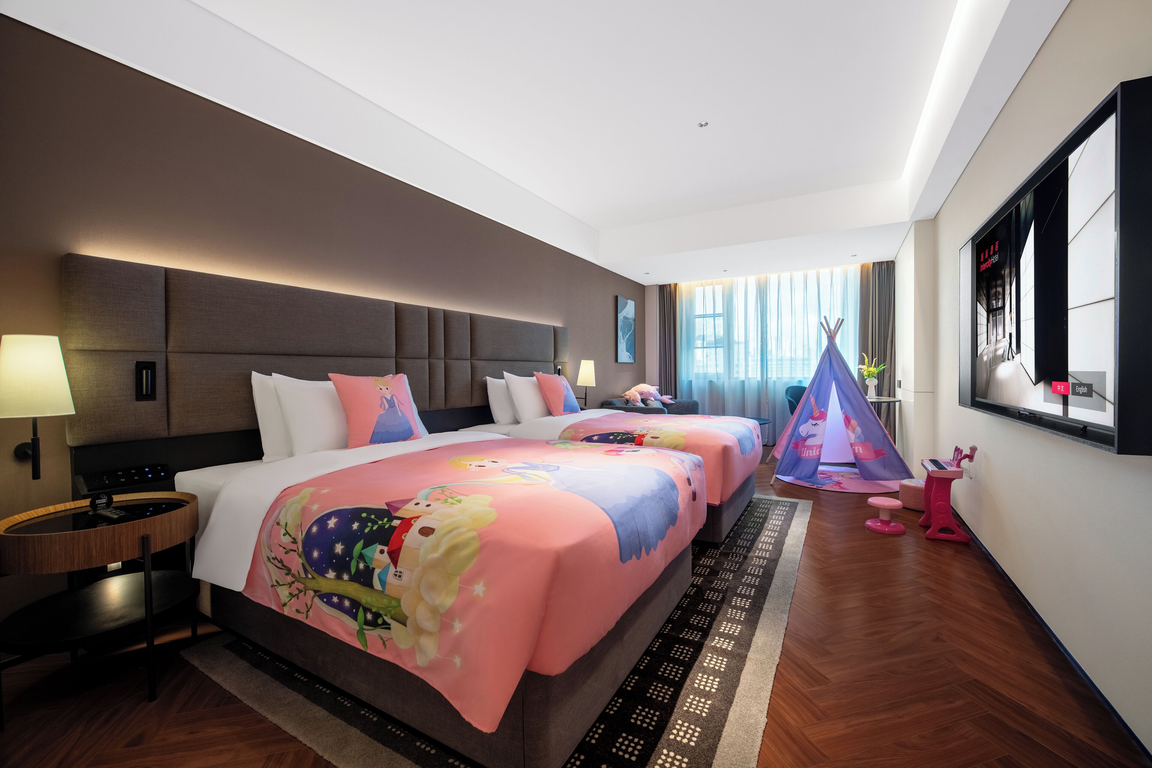 A hotel room with two beds, a desk, a chair, a window, and a tent.
