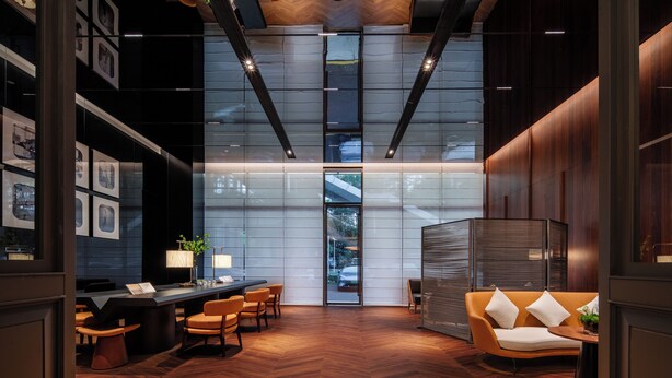 A modern interior with a herringbone wooden floor, a reception desk, and a seating area with a sofa and chairs.