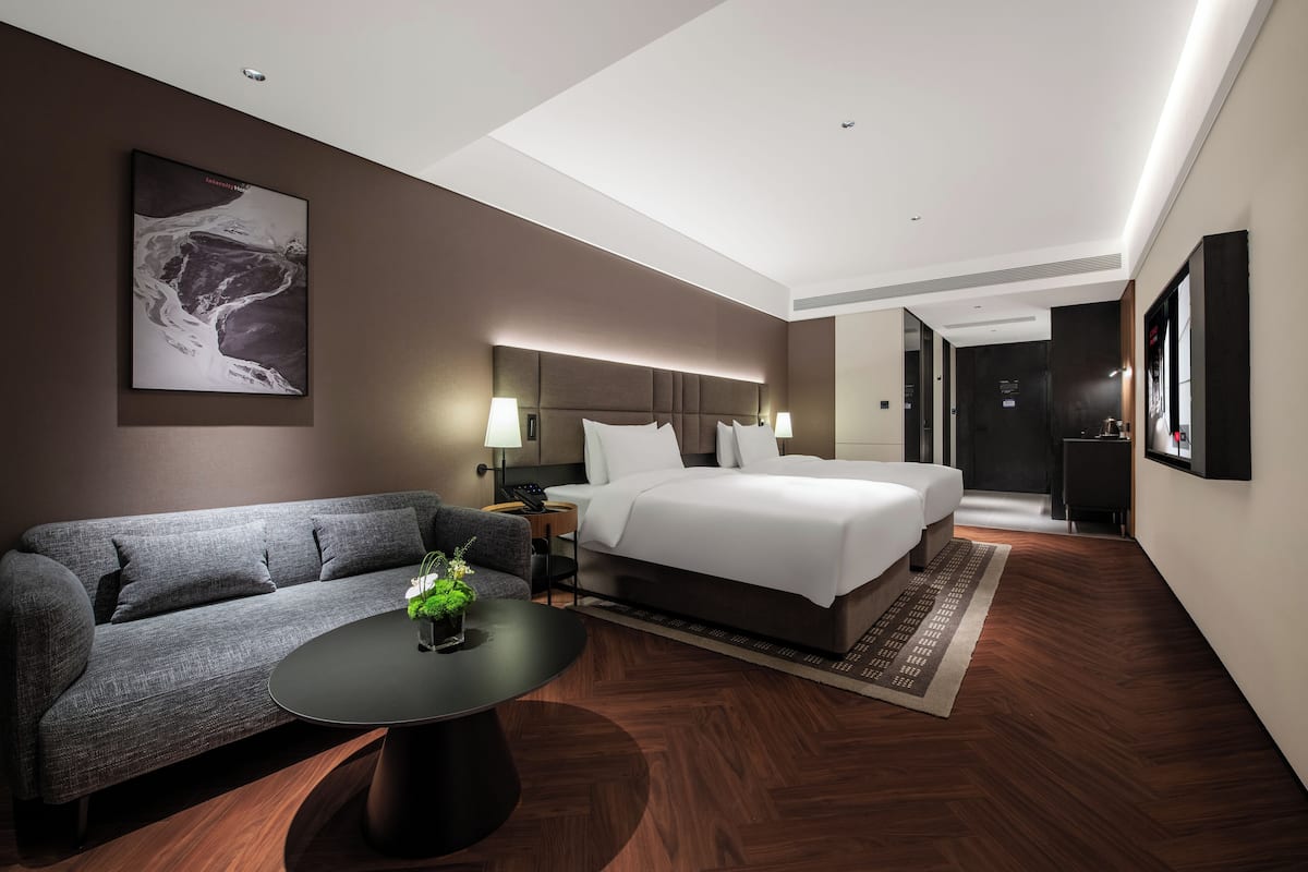 Una habitación de hotel moderna con una cama grande, un sofá, una mesa de centro y un cuadro en la pared.