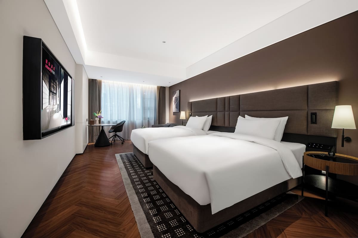 Una habitación de hotel con una cama grande, mesitas de noche, un escritorio y una silla.