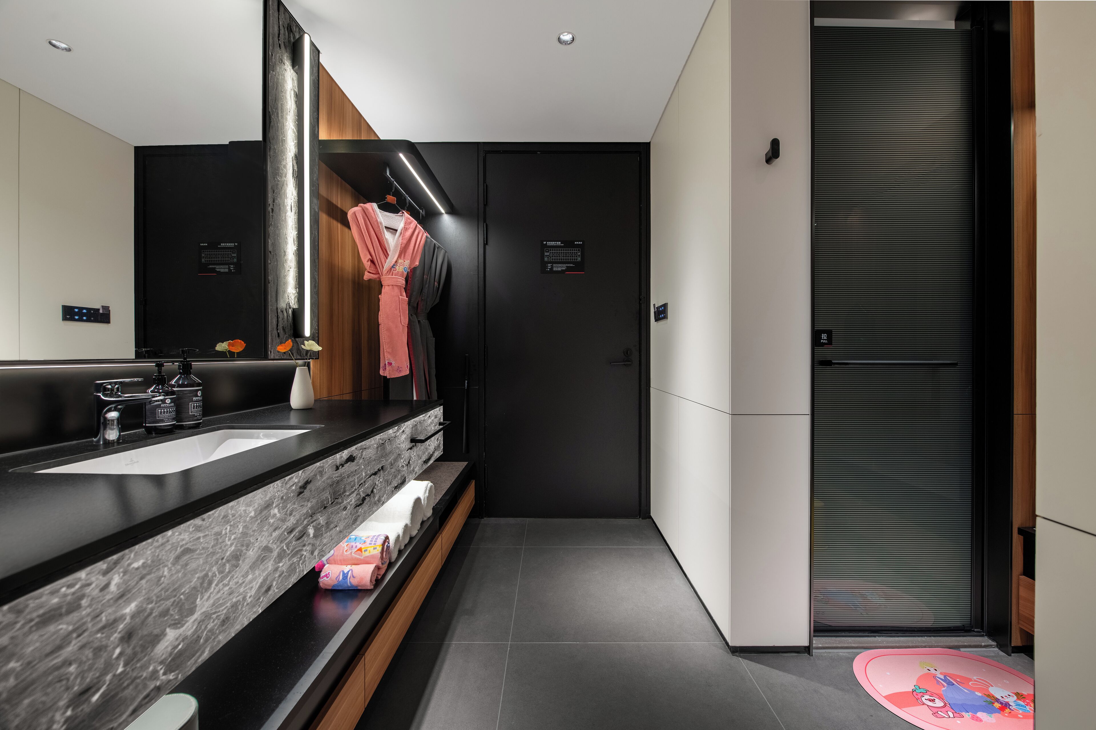 Une salle de bain moderne avec un lavabo noir, un miroir et des meubles aux teintes sombres.