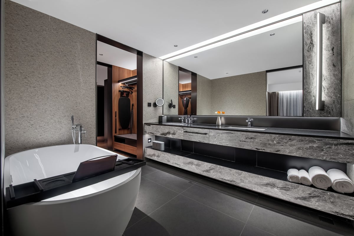 Un baño moderno con una bañera grande, un tocador con espejo y un perchero para toallas.
