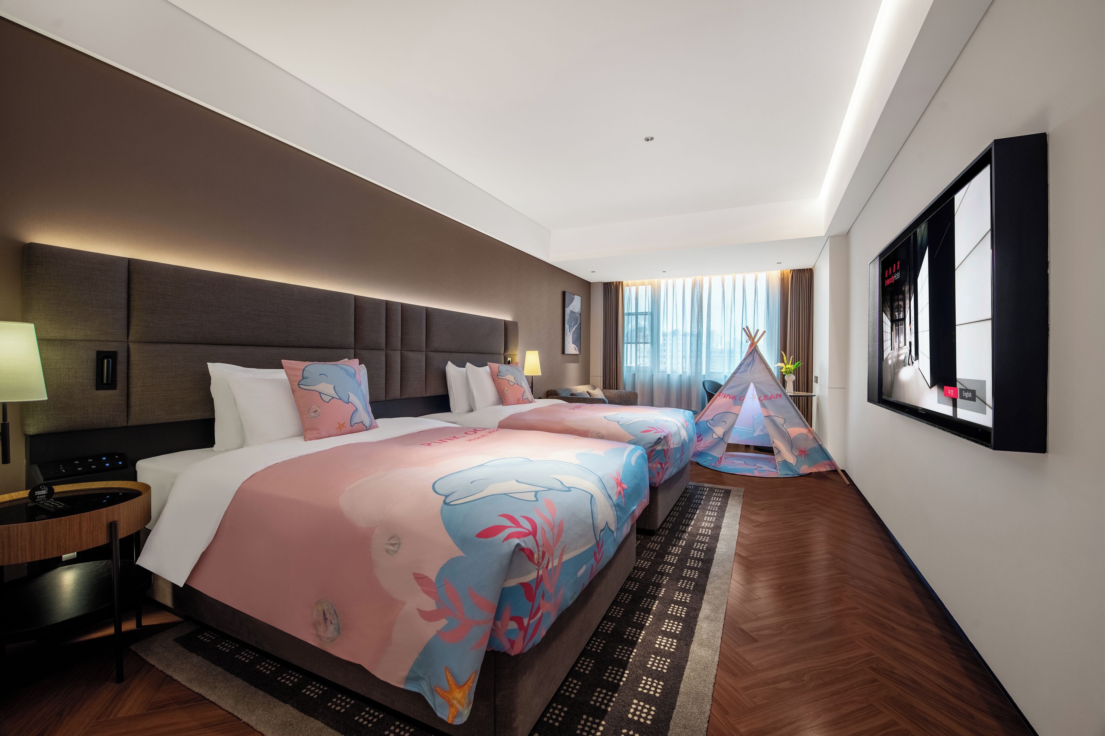 Een hotelkamer met een groot bed, een bureau, een televisie en een raam met gordijnen.