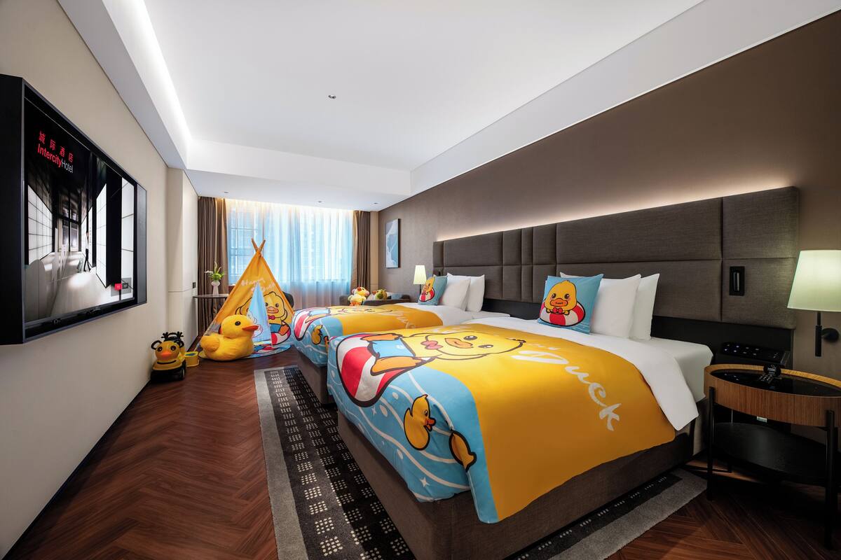 Habitación de hotel con una cama grande, un escritorio pequeño, una ventana con cortinas y un televisor de pared.