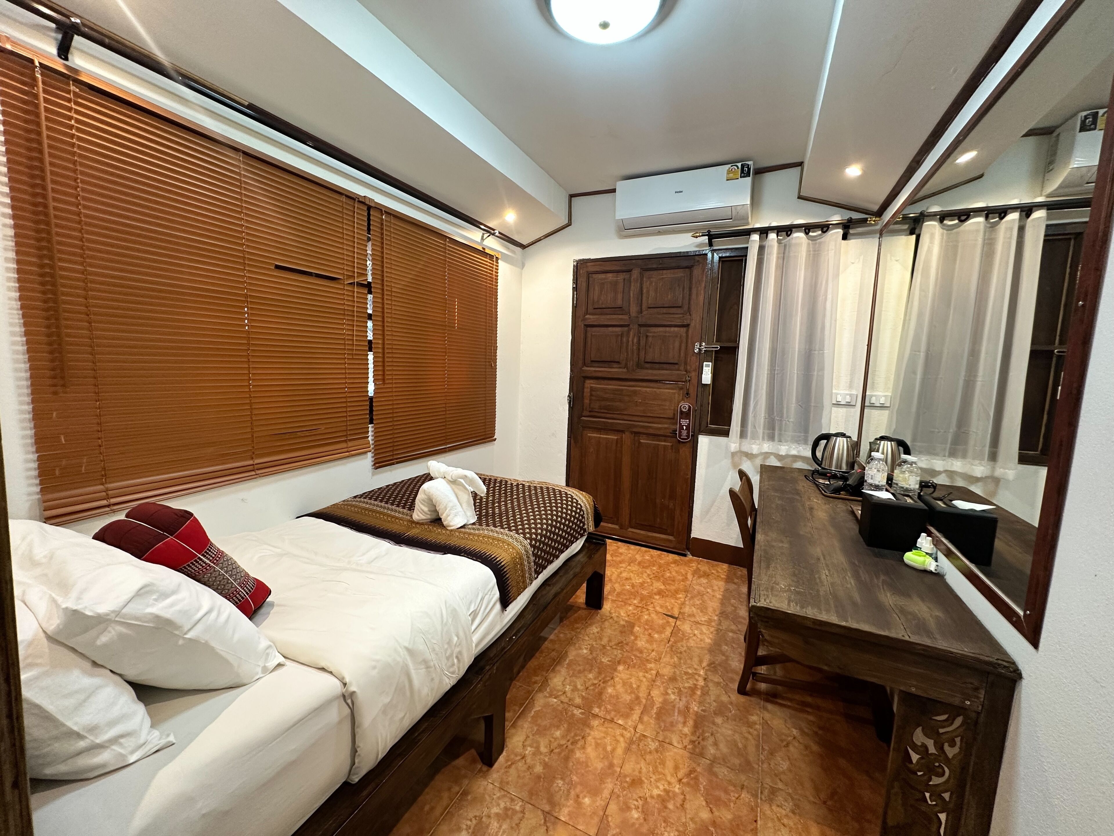 Une chambre à coucher avec un lit, une porte en bois, une table à manger avec des chaises et un appareil de climatisation.