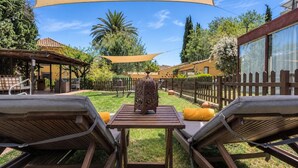 A patio with two lounge chairs, a table, and a decorative metal sculpture. - Guestready - Hotel Rural Las Calas (Vega de San Mateo)