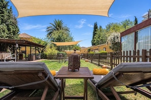 Un patio con dos sillones de descanso, una mesa y una escultura metálica decorativa.