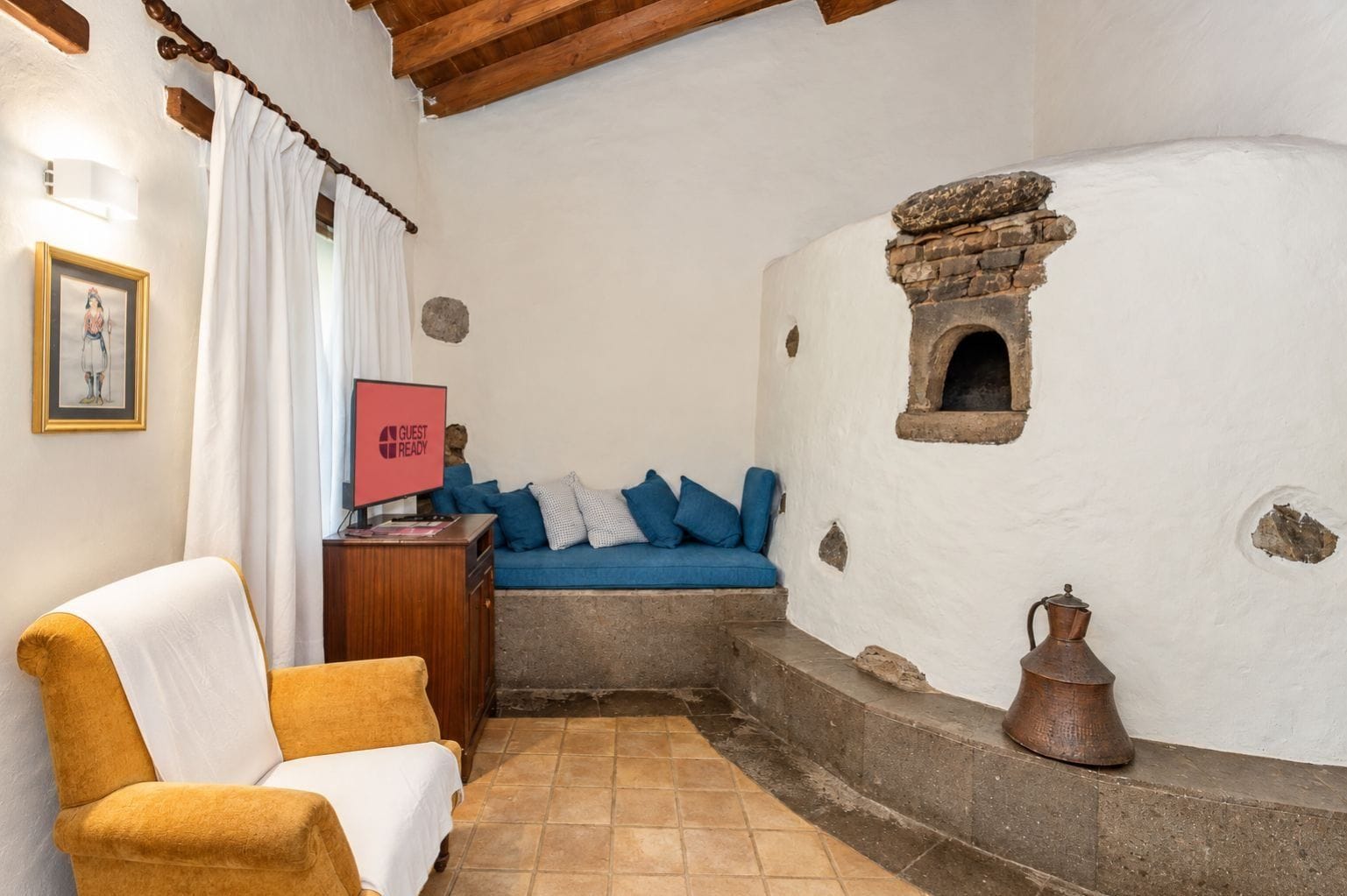 Una habitación acogedora con un sofá, una silla, una mesa con un letrero rojo y una pared de piedra con un ventanal pequeño.