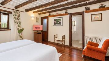 Een hotelkamer met een bed, een stoel, een televisie en een douche.