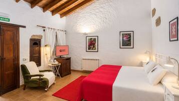 Habitación de hotel con cama, escritorio, silla, televisor y alfombra roja.