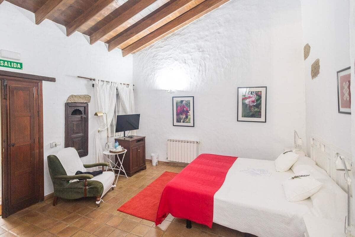Una habitación con una cama, una silla, un televisor, un radiador y un cartel que dice 'SALIDA'.