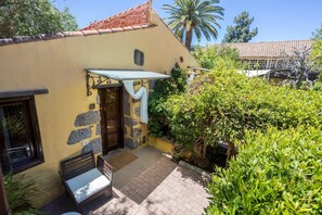 A yellow building with a stone facade, a wooden door, and a bench outside. - Guestready - Hotel Rural Las Calas (Vega de San Mateo)