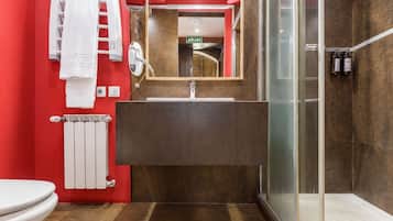 Un baño moderno con cabina de ducha de vidrio, inodoro blanco, toallero y espejo sobre el lavamanos.