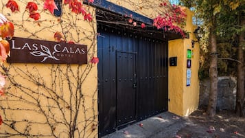 Entrada de hotel con una reja negra, un letrero que dice 'Las Calas Hotel' y un pequeño letrero que indica acceso para personas con movilidad reducida.