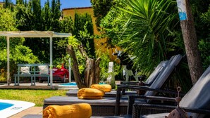 A poolside area with lounge chairs, a bench, and a covered seating area. - Guestready - Hotel Rural Las Calas (Vega de San Mateo)