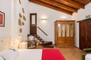 Una habitación de hotel con una cama, un armario de madera, una escalera y una puerta con la inscripción 'SALIDA'.