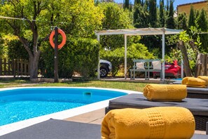 Ein Schwimmbecken mit Liegestühlen, Handtüchern, einem Rettungsbojen und einem überdachten Sitzbereich.
