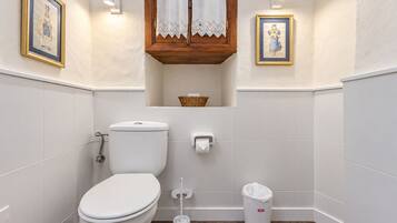 A bathroom with a toilet, bidet, and trash can.