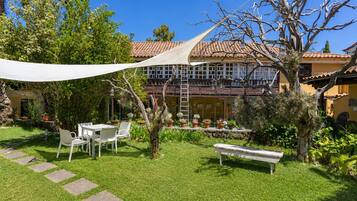 A courtyard with a white table and chairs, a bench, and a variety of potted plants.