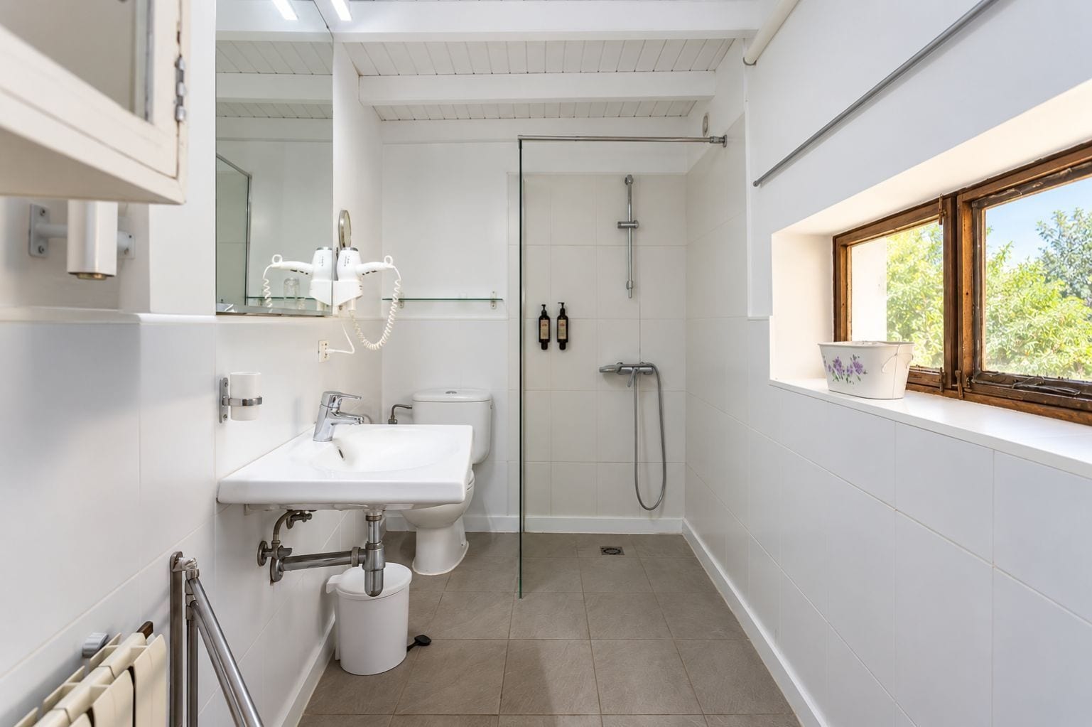 Un baño moderno con lavamanos, inodoro y ducha blancos.