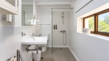 Un baño moderno con lavamanos, inodoro y ducha blancos.