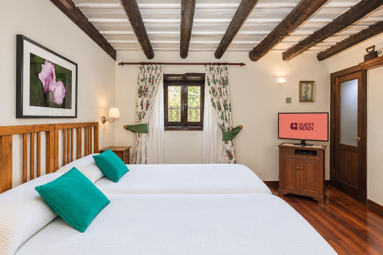 Habitación de hotel con una cama grande, cabecera de madera, televisor de pantalla plana y ventana con cortinas.