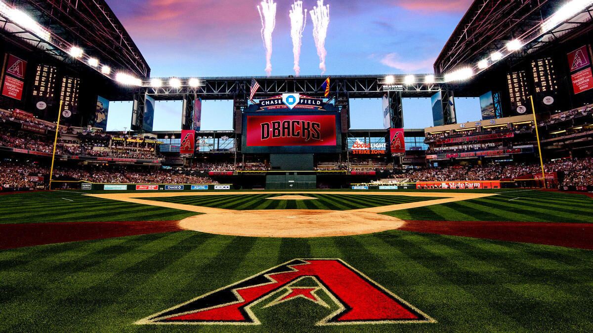 A baseball stadium with a large screen displaying 'DBACKS' and Chase Field branding.