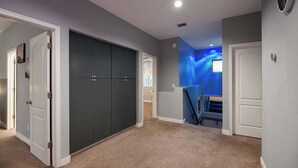 Een gang met een tapijtvloer, een donkere kast en een trap die naar een kamer met een blauwe muur leidt.