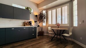 A modern kitchen with dark cabinets, a marble countertop, and a dining area with a round table and two chairs. - Relaxing 5BR Tempe Home family pool moder home (Tempe)
