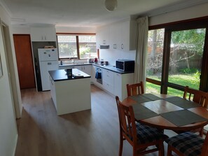 Eine moderne Küche mit weißen Schränken, einer zentralen Kochinsel und einem Essbereich mit Tisch und Stühlen.