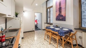 A kitchen with a gas stove, a sink, and a dining area with a table set for two. - Da Stefano Historical Center 5 min to Aquarium (Genoa)