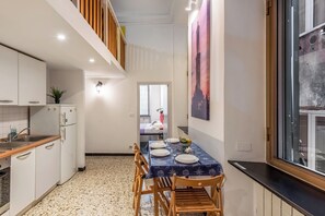 A modern kitchen with white cabinets, a wooden countertop, and a dining area with a table set for four. - Da Stefano Historical Center 5 min to Aquarium (Genoa)