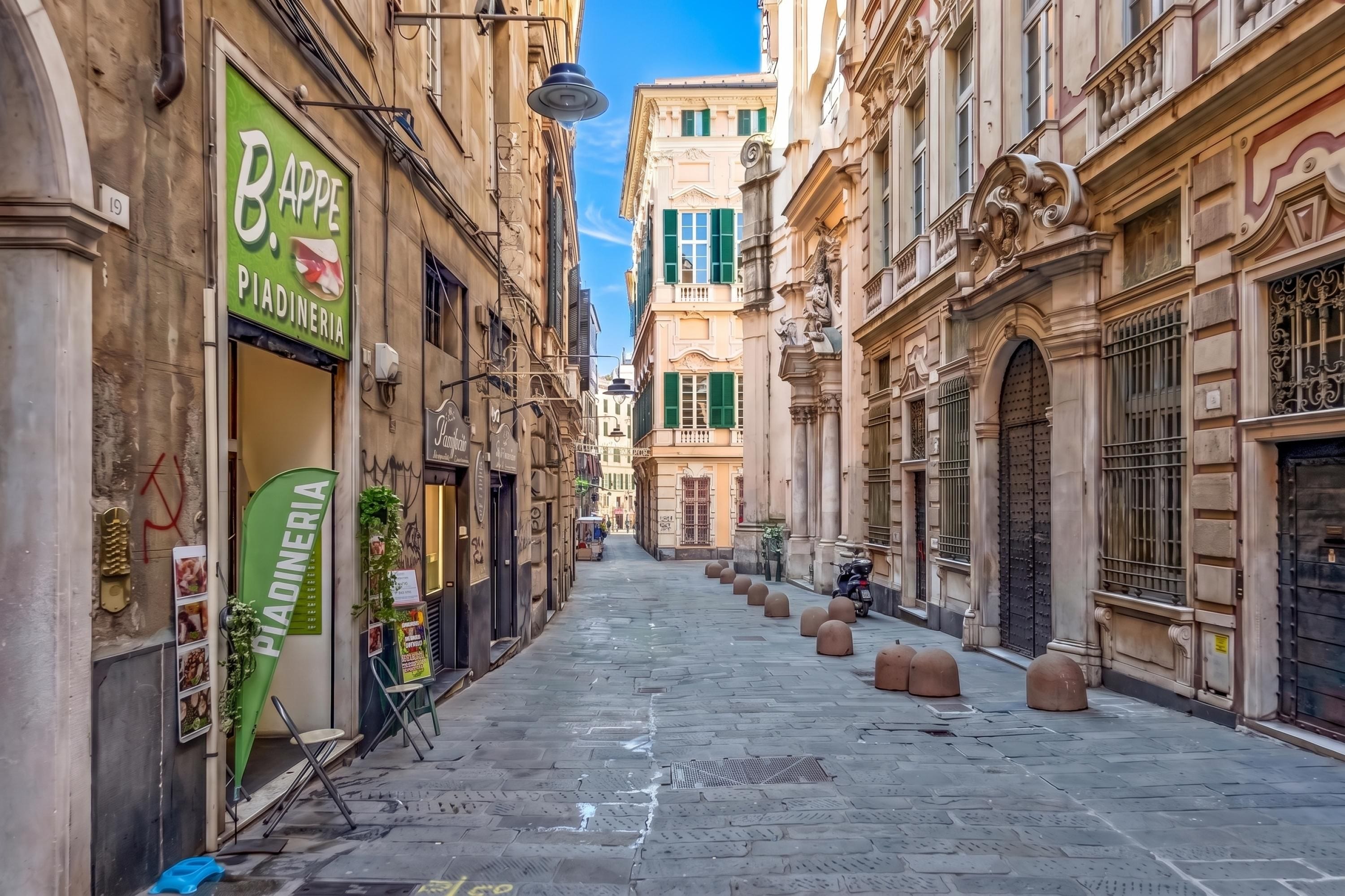 Una calle estrecha con edificios históricos, un letrero de restaurante y bolardos a lo largo de la acera.