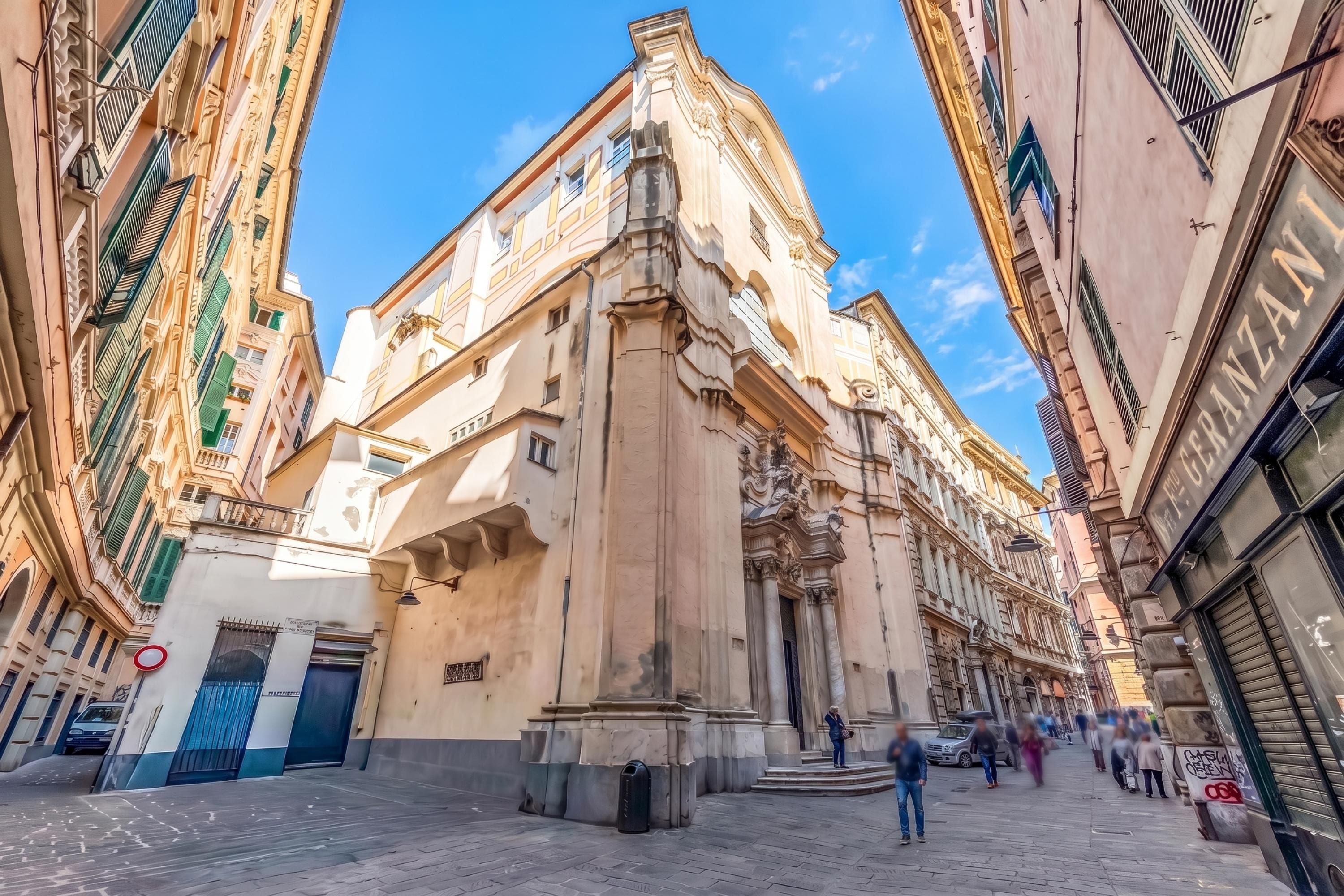 A street with historic buildings, a statue, and a clear blue sky.