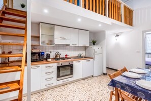 A compact kitchen with white cabinets, a stove, a microwave, and a refrigerator. - Da Stefano Historical Center 5 min to Aquarium (Genoa)