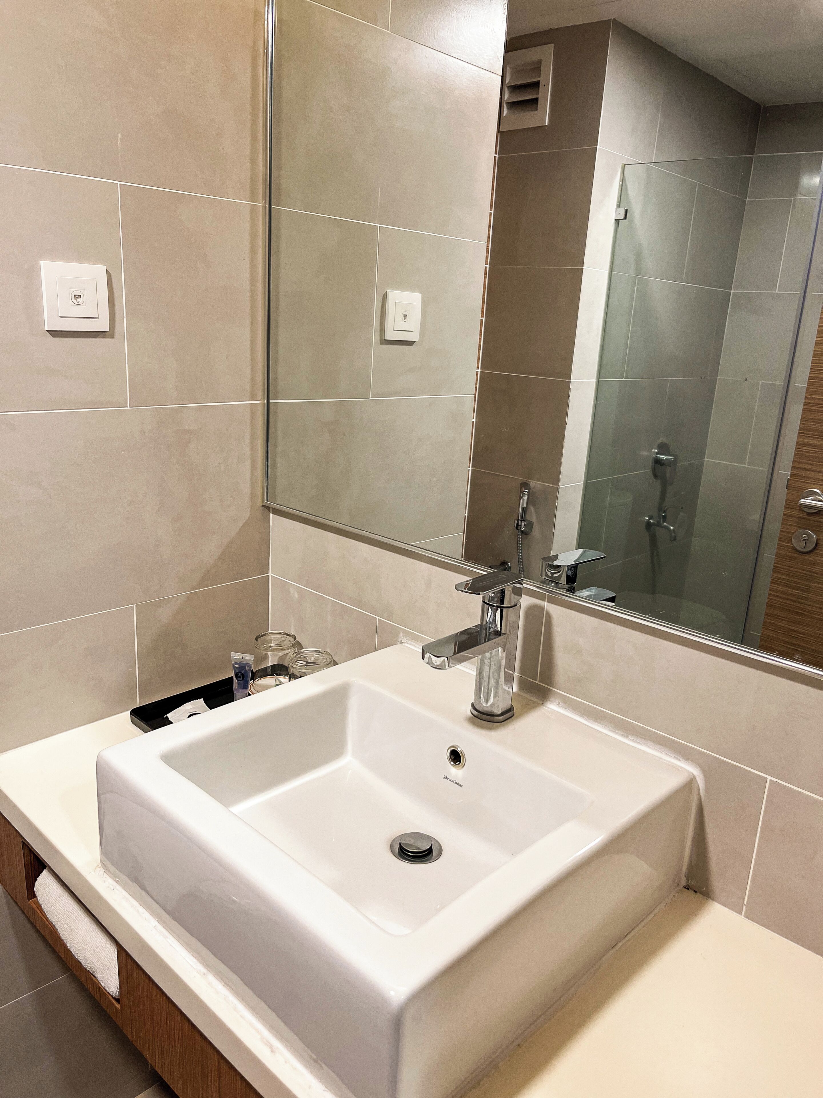 Un baño con lavamanos blanco, un espejo y zona de ducha.