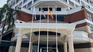 Un hotel de varios pisos con una entrada destacada, una columna central y varias banderas.