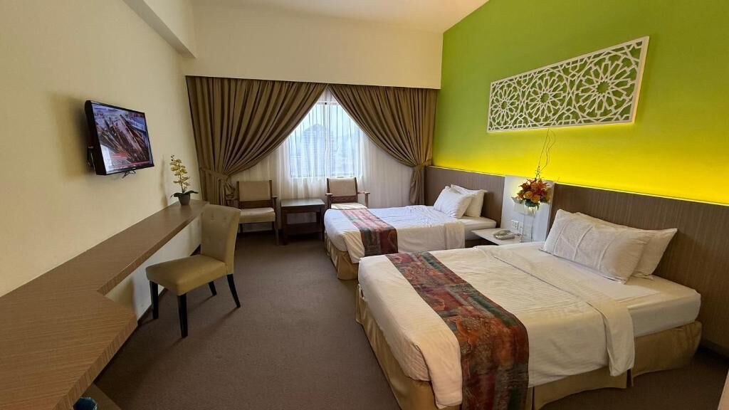 Habitación de hotel con dos camas, un escritorio, una silla, un televisor y un panel decorativo en la pared.