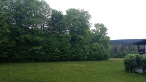 A building with a red roof, surrounded by dense green trees and a grassy field. - House Begonia Room No. 5 (Siegsdorf)