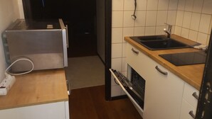 A compact kitchen with a built-in microwave, a sink, and a dishwasher. - House Begonia Room No. 5 (Siegsdorf)
