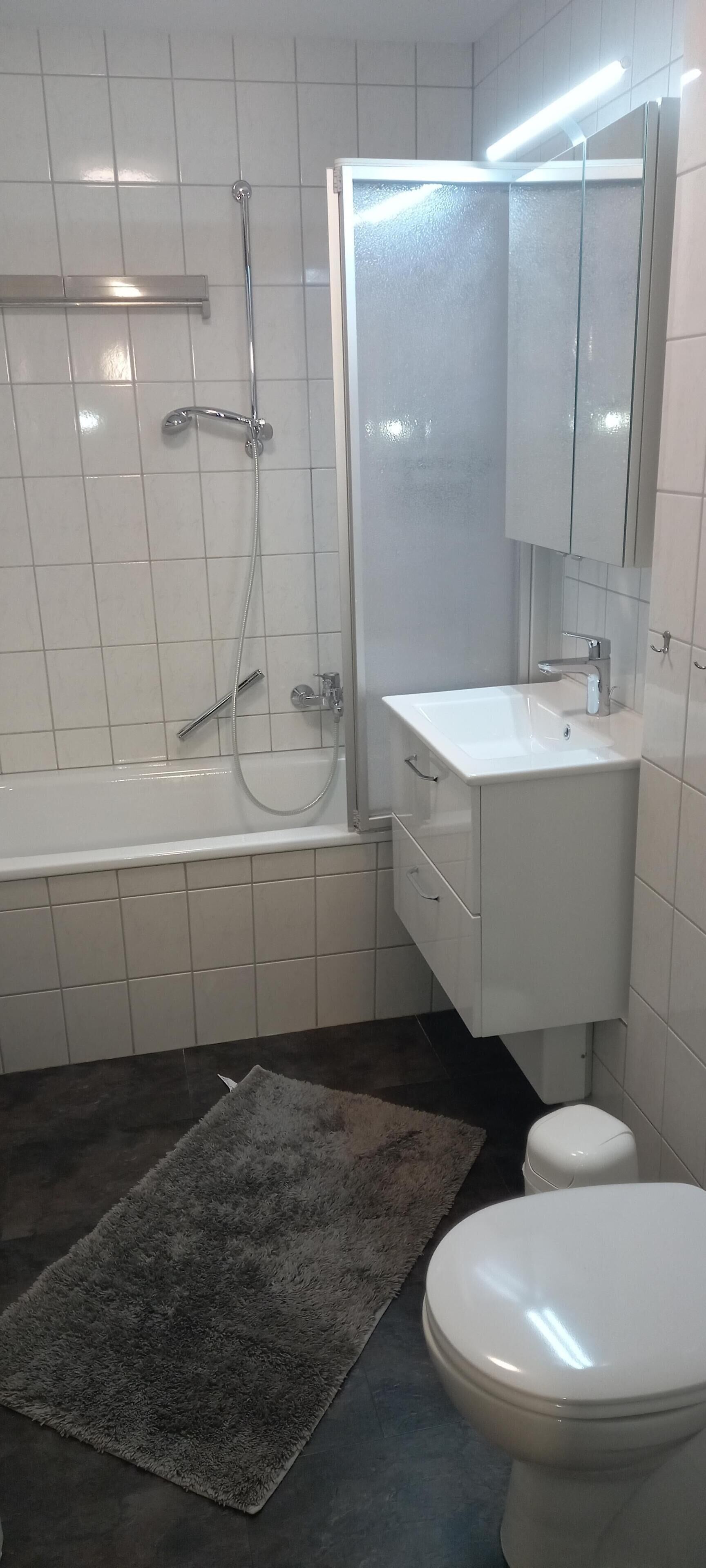 Een badkamer met een bad, toilet, wastafel en spiegel.