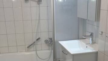 Een badkamer met een bad, toilet, wastafel en spiegel.