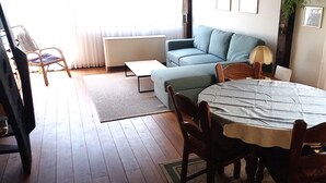 A living room with a sofa, a dining table, and a chair. - Vacation apartment type C/Salzburg (Siegsdorf)
